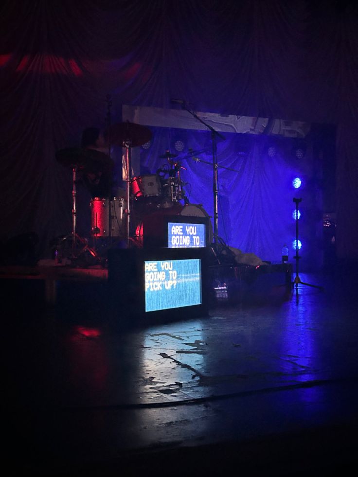 the stage is set up for an event with blue lights and drapes on it