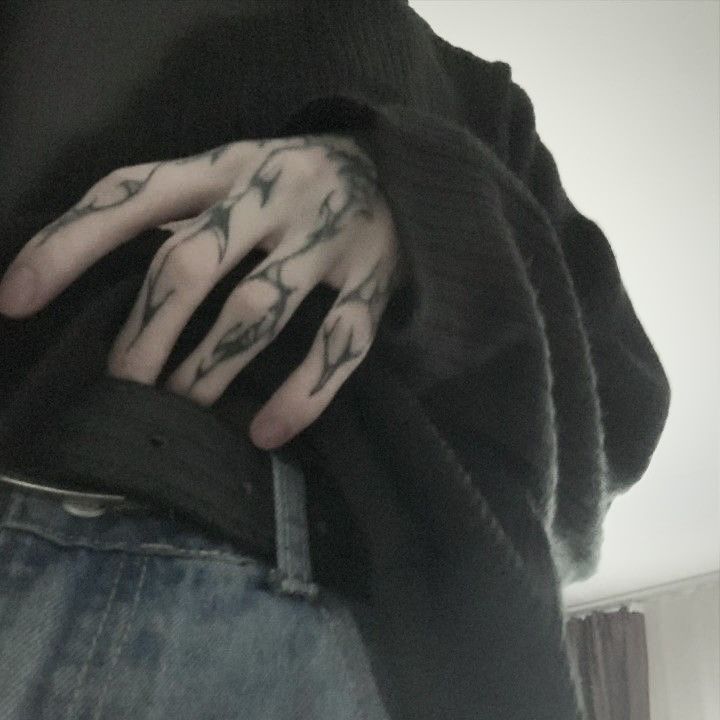 a person with tattoos on their hands holding onto his hand and wearing a black sweater