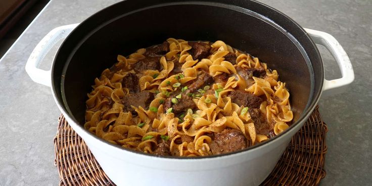 a pot filled with pasta and meat on top of a table