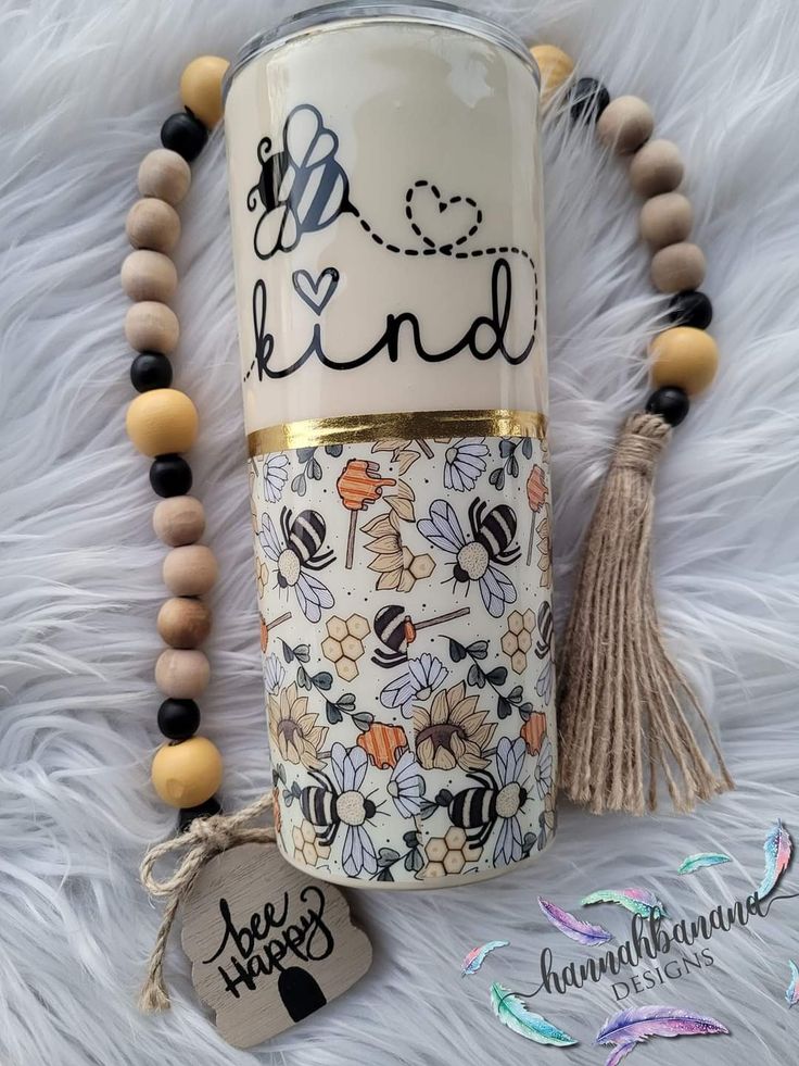 a coffee cup with beads and a tassel on it next to a tag that says, be kind