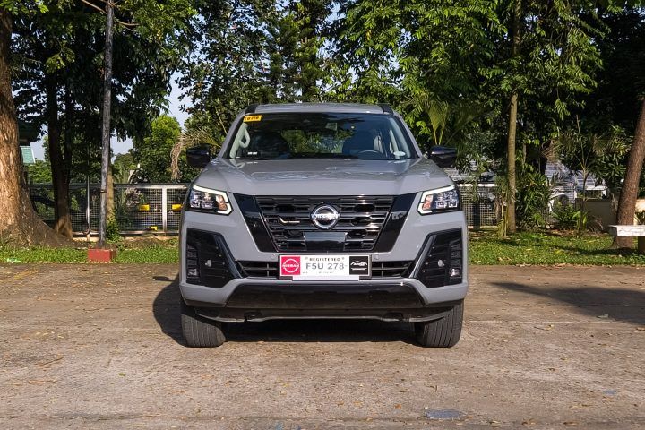 the front end of a silver nissan pickup truck parked in a parking lot with trees behind it