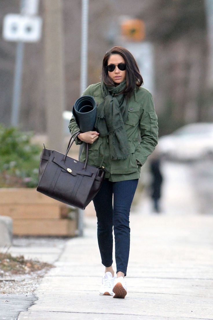 a woman walking down the street carrying a brown purse