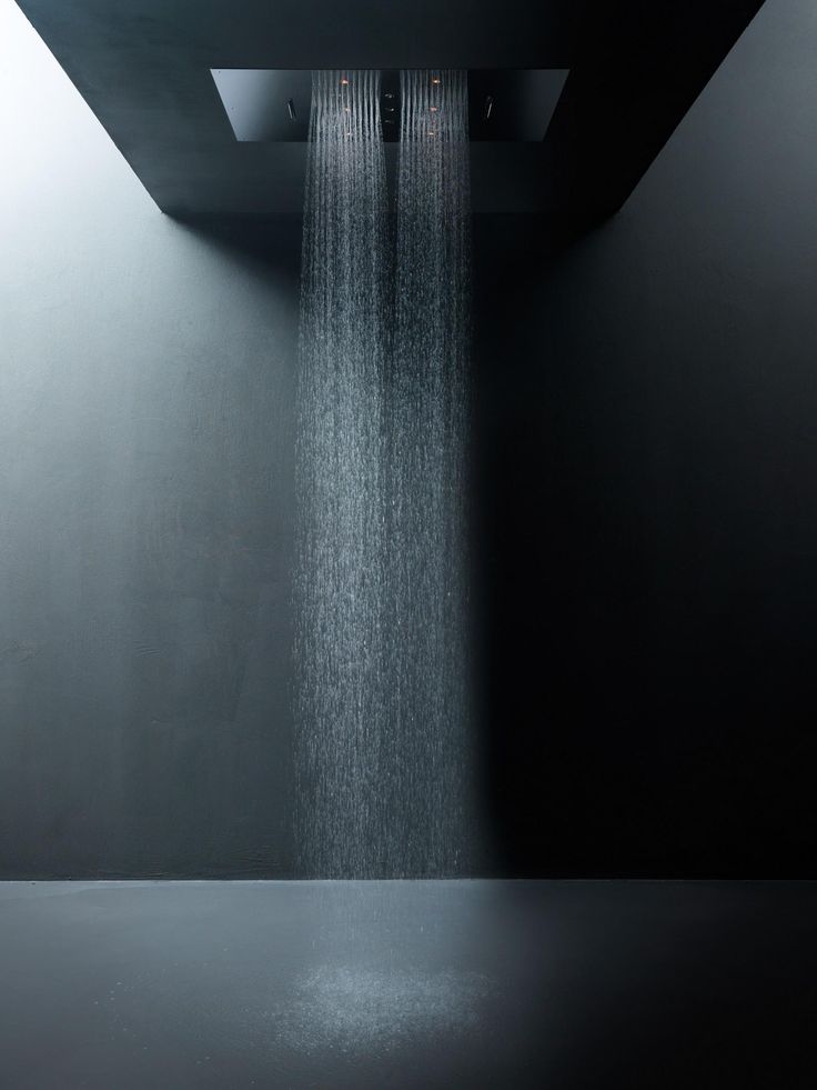 a shower head with water flowing from it's sides in a black and white room