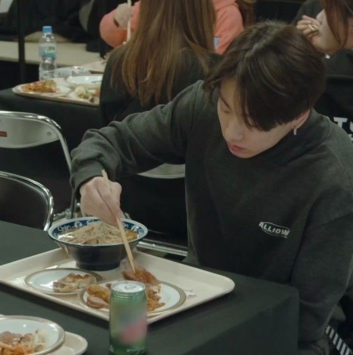 a person sitting at a table with food in front of him and eating from a bowl