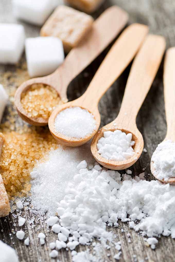 spoons filled with sugar and sugar cubes on top of a table