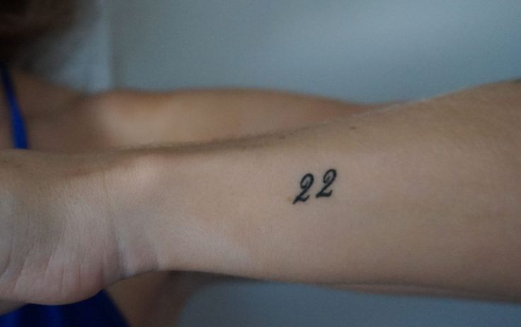 a person's arm with a small tattoo that reads 922 on the wrist