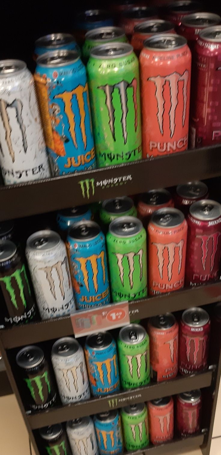 several cans of monster energy drink are stacked on a shelf in a store display case