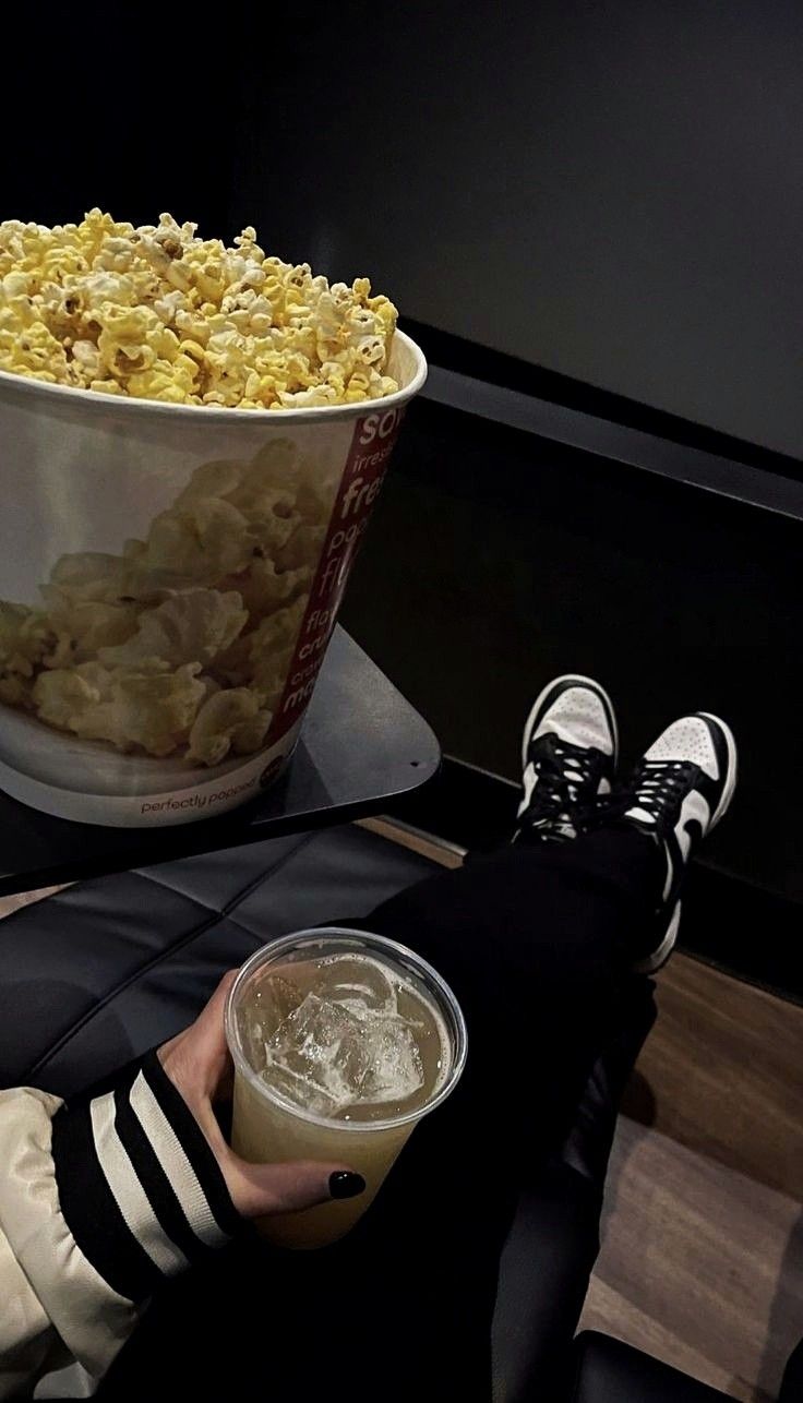 a person sitting on a chair with their feet up next to a bowl of popcorn