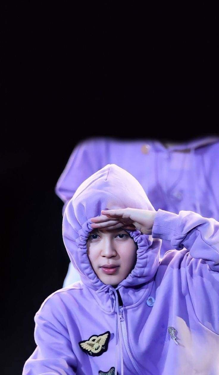 a woman in a purple jacket is holding her hand on her head