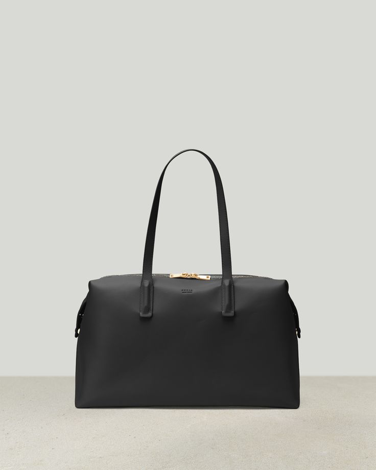 the large black leather bag with gold hardwares is shown on a white surface, and it