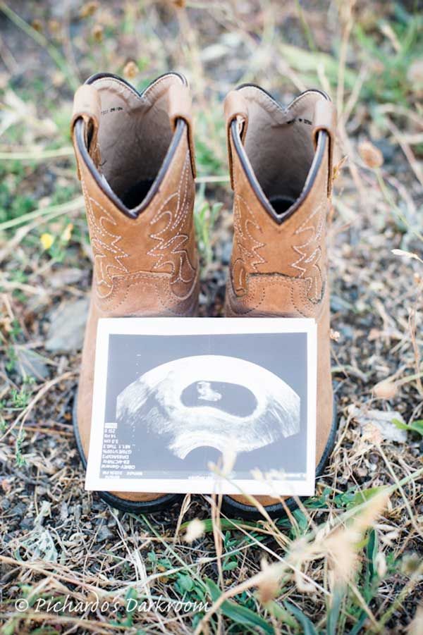 a pair of brown cowboy boots sitting on top of the ground next to a plaque