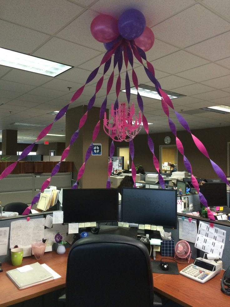 an office cubicle decorated with purple streamers and pink balloons hanging from the ceiling