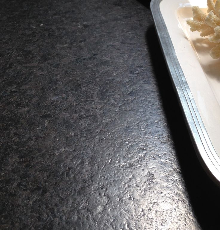 a white plate topped with food on top of a black counter next to a fork