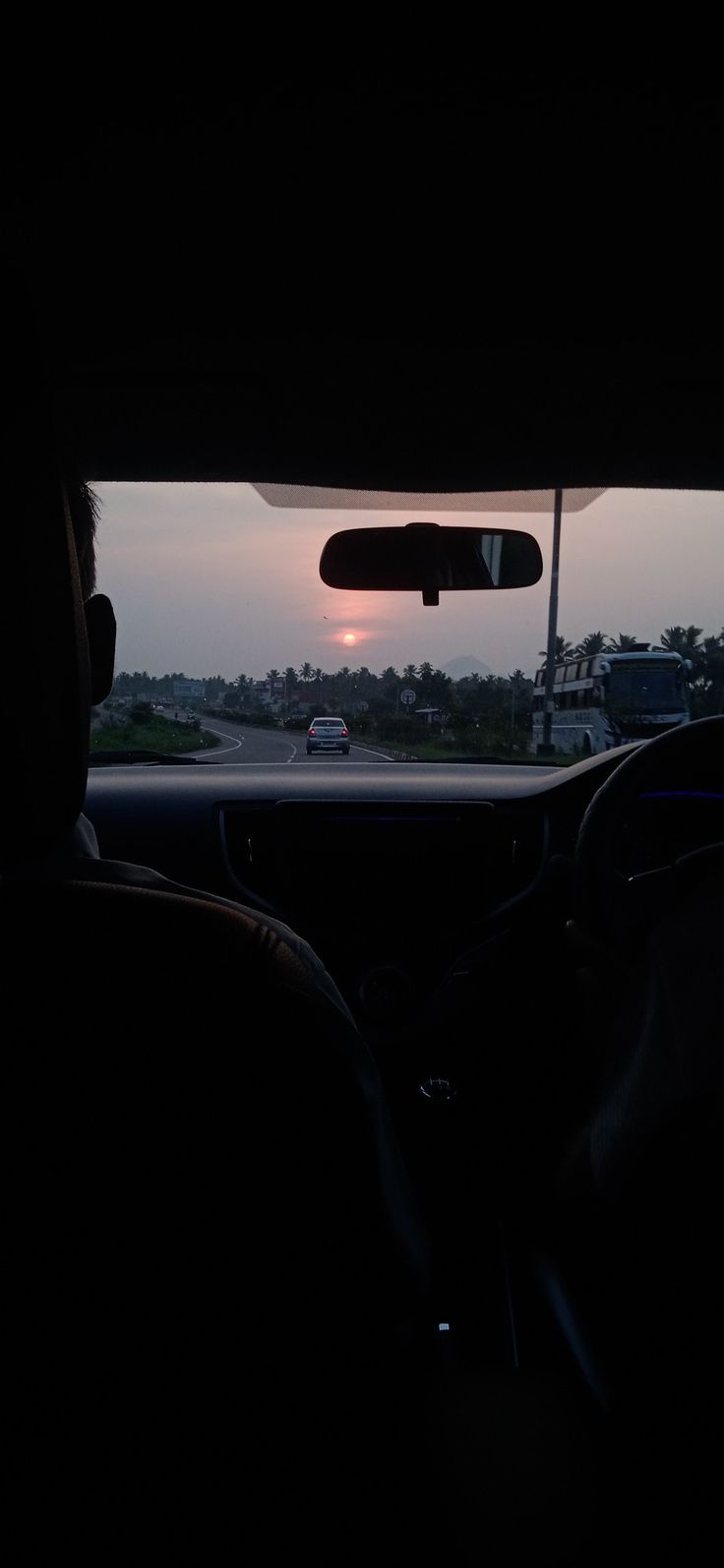 the sun is setting in the distance as seen from inside a car's passenger seat