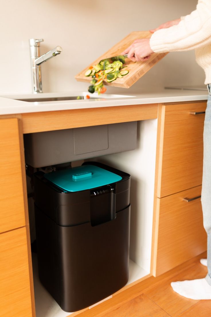 a person holding a cutting board over a trash can