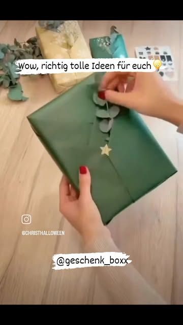 a person is opening a green gift box on the table with other gifts around it