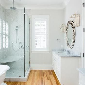 a white bathroom with wood flooring and glass shower stall, sink, and bathtub