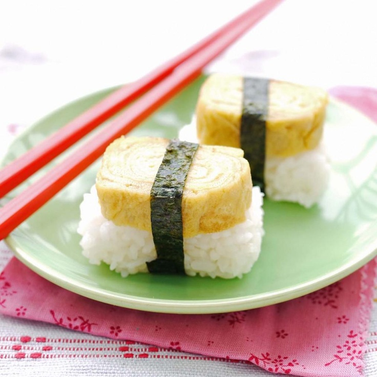 two pieces of sushi on a green plate with chopsticks next to it