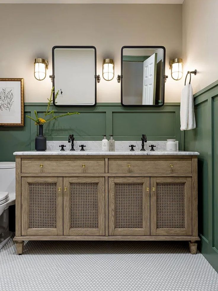 a bathroom with green walls and two mirrors on the wall above the double sink vanity