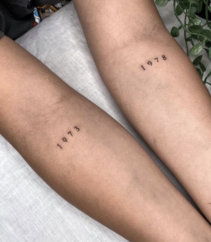 two people with tattoos on their legs sitting next to each other and one has the word love