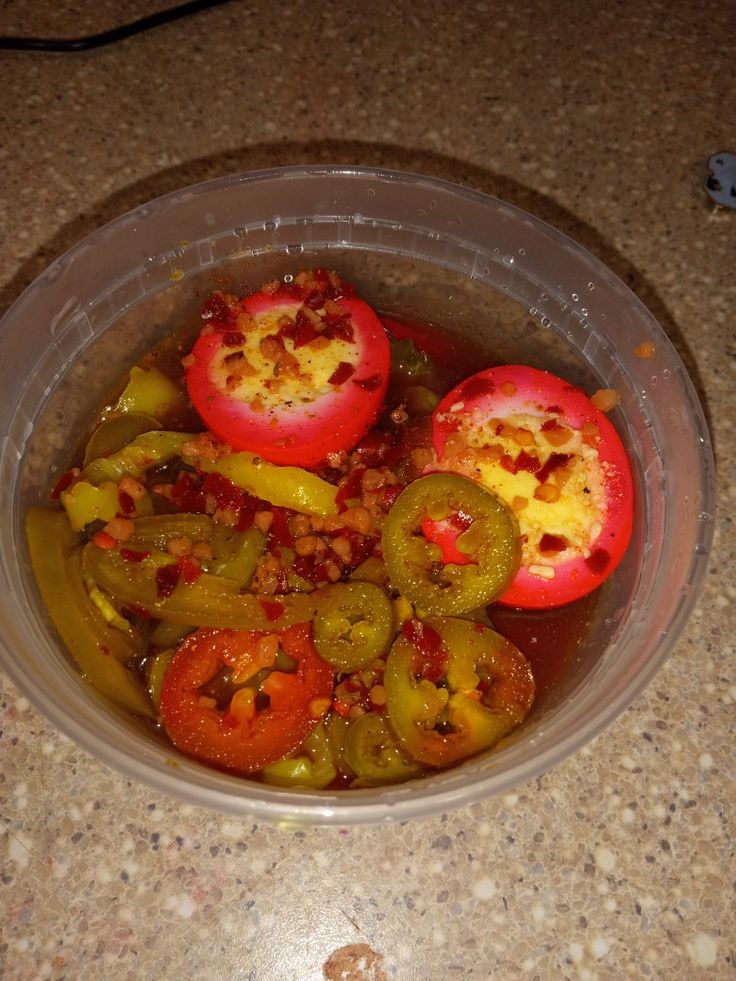 a plastic bowl filled with sliced up tomatoes and peppers on top of a granite counter