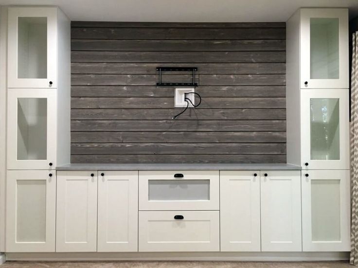 an entertainment center with white cabinets and wood paneling