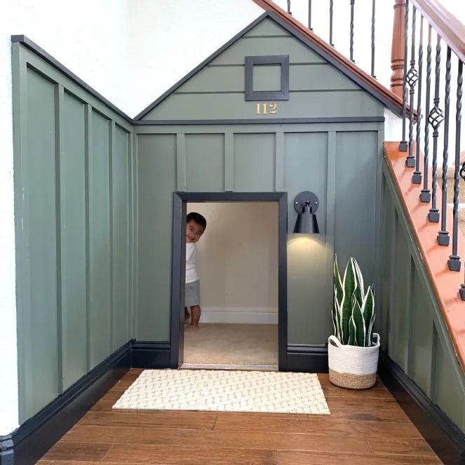 a little boy standing in the doorway of a dog house that is built into the floor