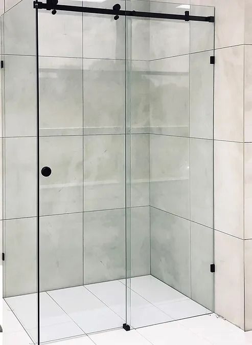 a walk in shower sitting next to a white tiled wall and floor with glass doors