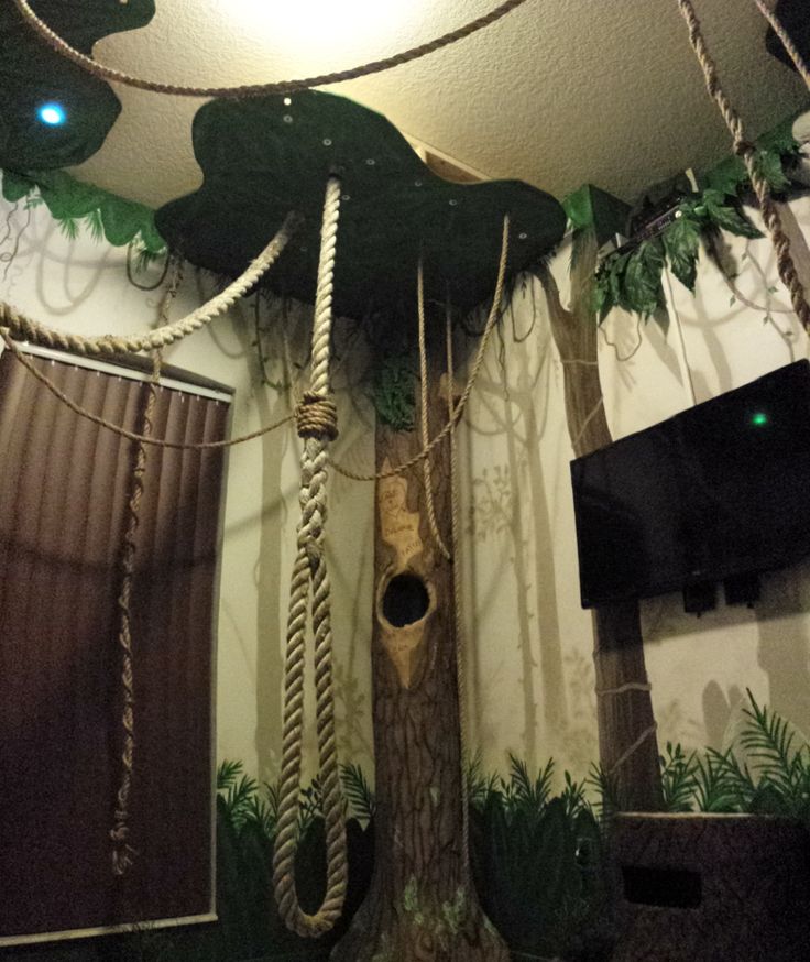 a tree with ropes hanging from it's trunk and some lights on the ceiling