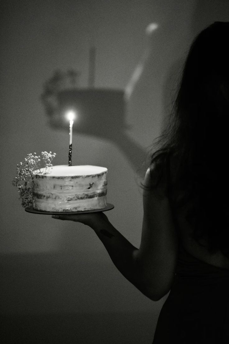 a woman holding a cake with a lit candle on it