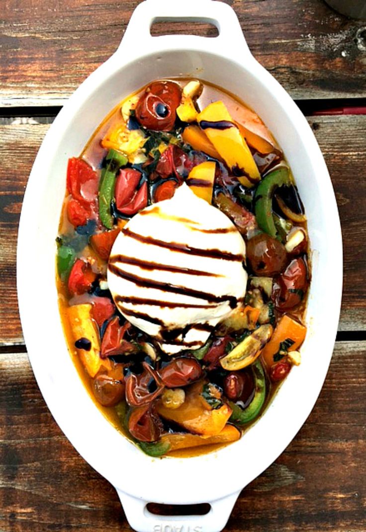 a white bowl filled with lots of different types of food on top of a wooden table