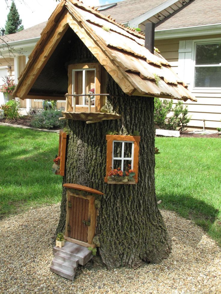 a tree house built into the side of a tree in front of a house with windows