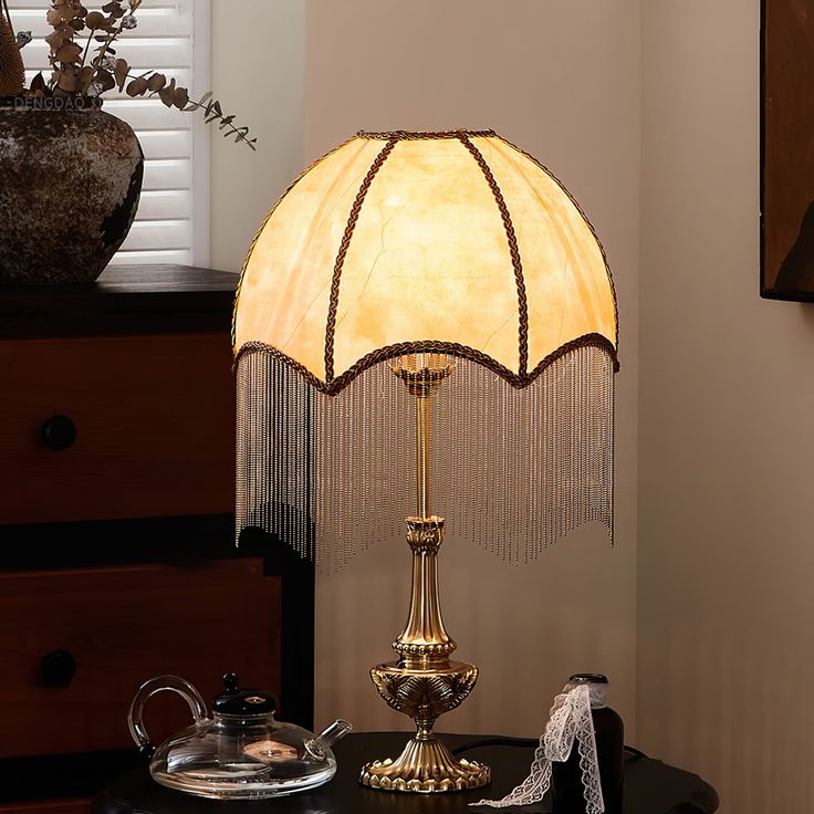 a lamp that is on top of a table next to a cup and saucer