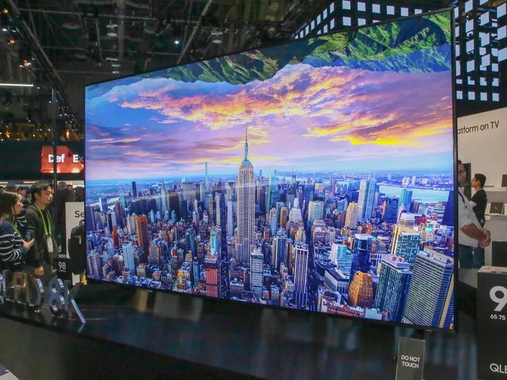 people are standing in front of a large television screen with the city skyline on it