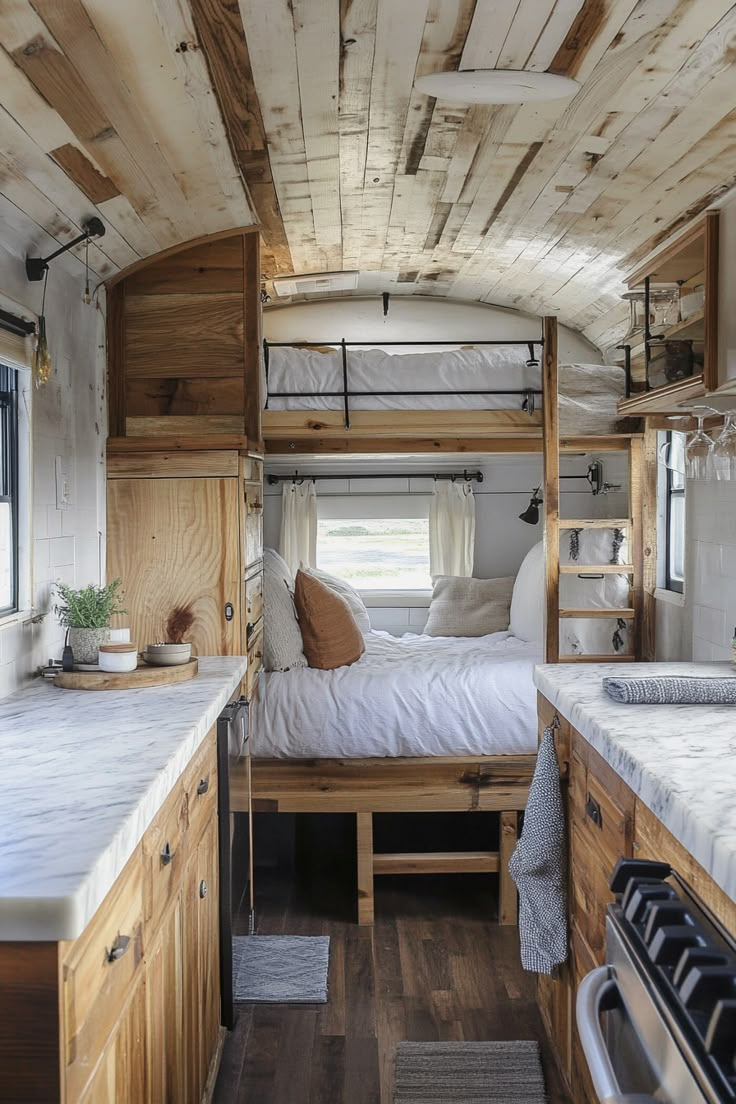 the interior of a small camper with wood paneling and white bedding, wooden floors