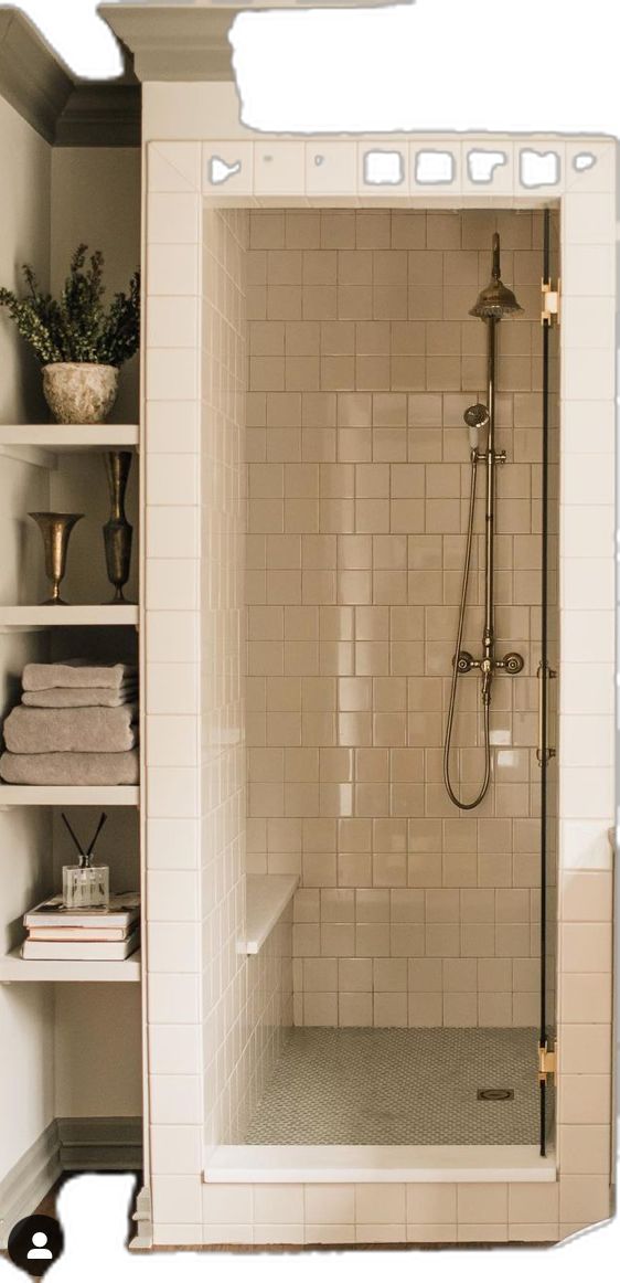 a walk in shower sitting next to a white shelf filled with books and vases