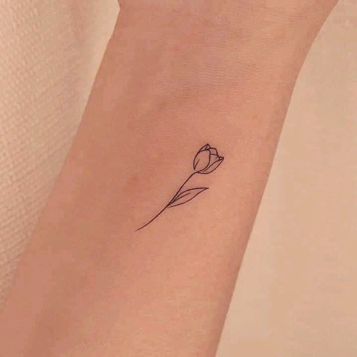 a small tattoo on the wrist of a woman with a single tulip in it