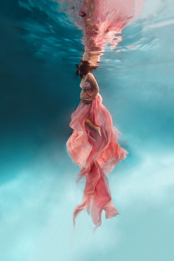 a woman in a pink dress under water