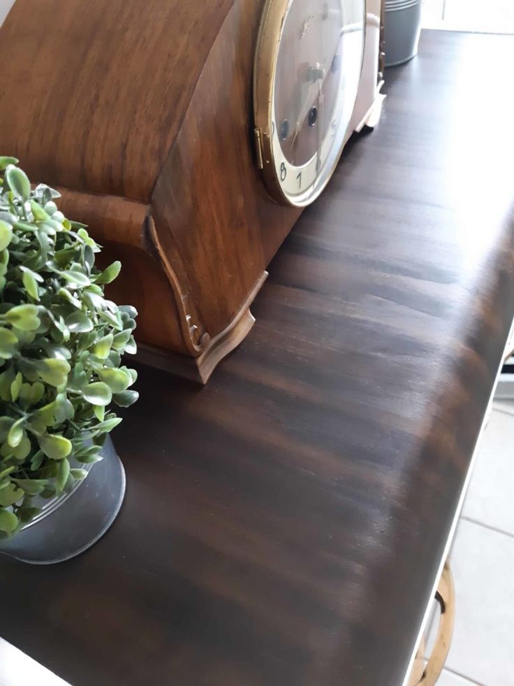 a clock sitting on top of a wooden table next to a potted green plant