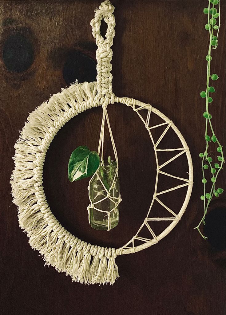 a hanging planter made out of rope with a glass vase in the center on top