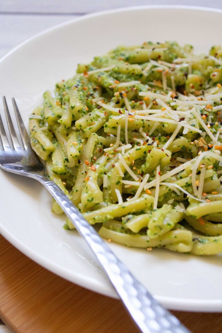 a white plate topped with pasta covered in pesto