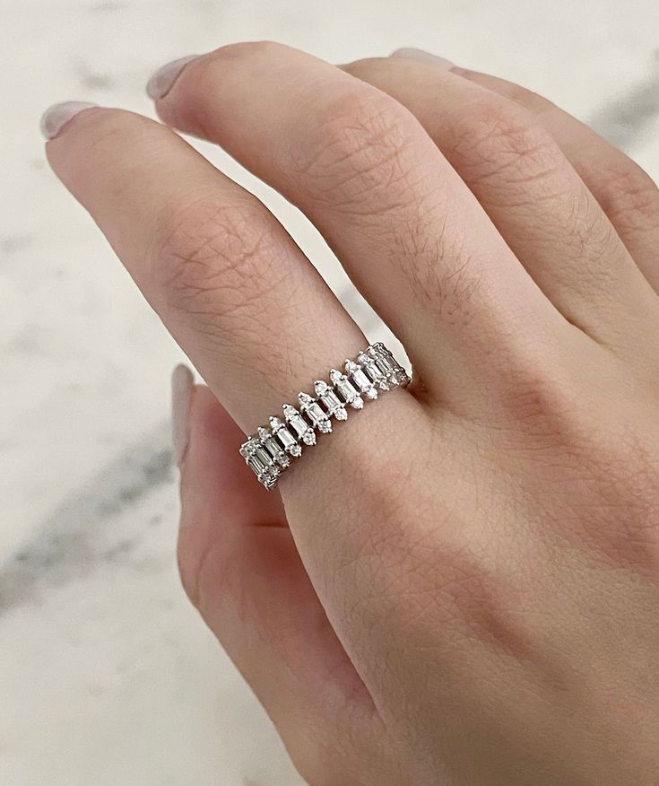 a woman's hand with a diamond ring on top of her finger, in front of a marble background