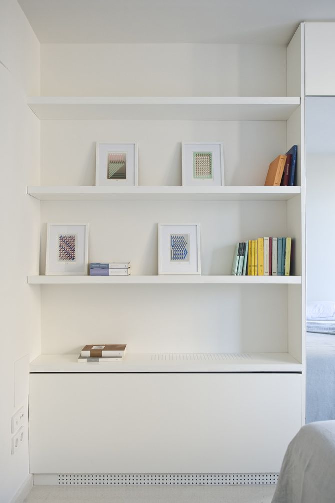 a white shelf with books and pictures on it