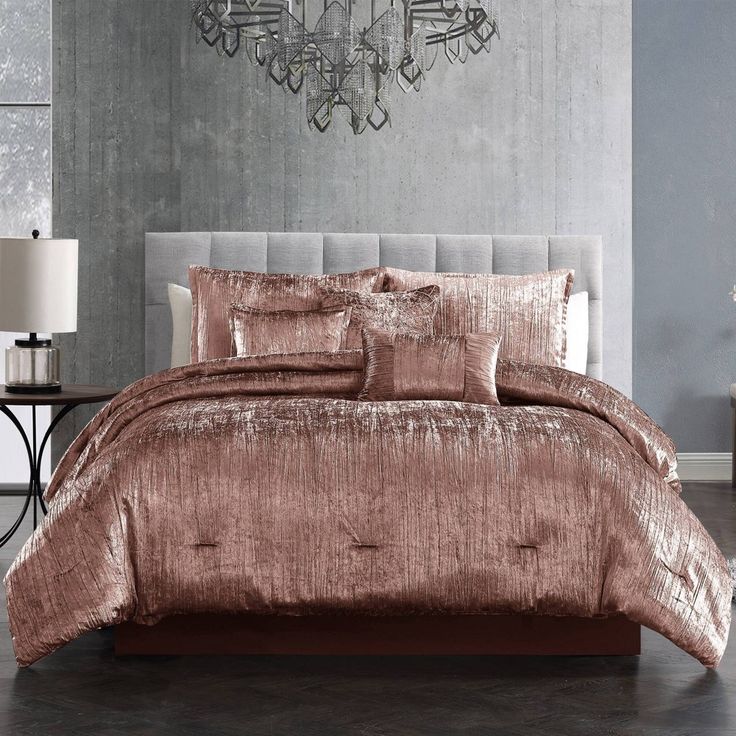 a bedroom with a chandelier and bedding in it, including a pink comforter