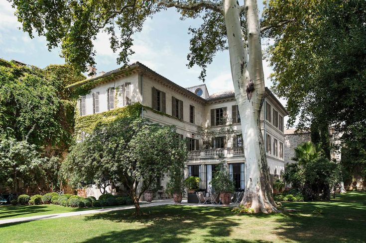 a large white house sitting on top of a lush green field next to a tree