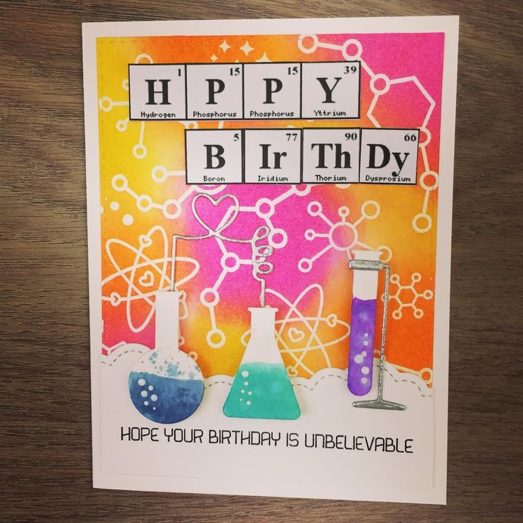 a happy birthday card with some science themed items in the background on a wooden table