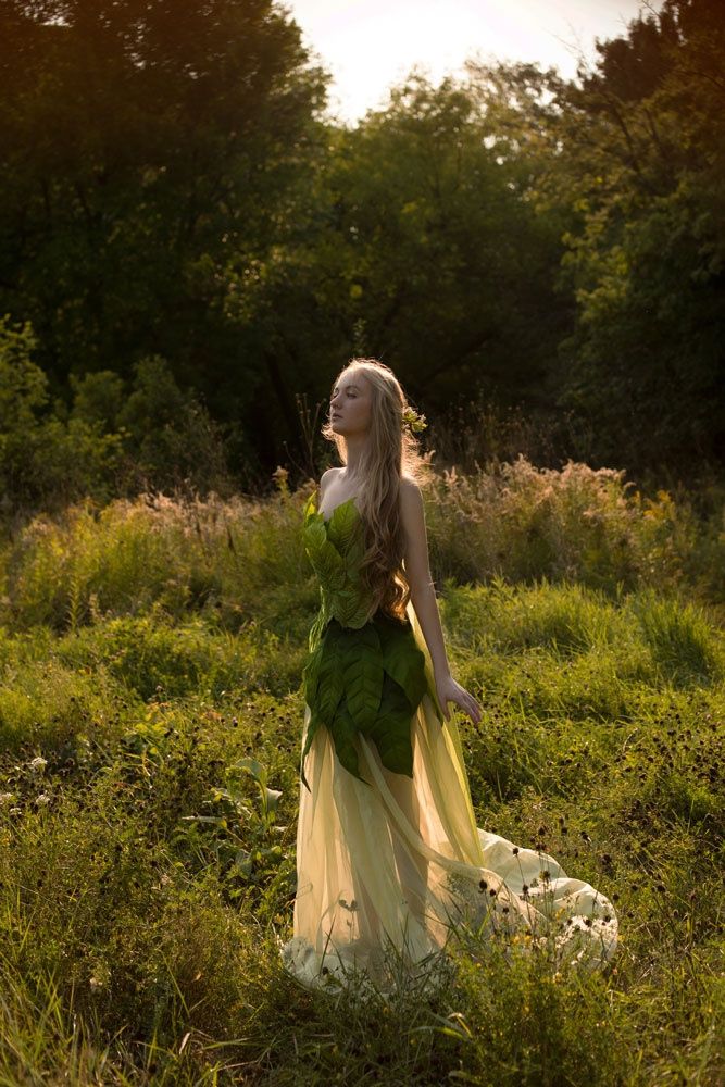 a woman in a green dress is standing in the grass