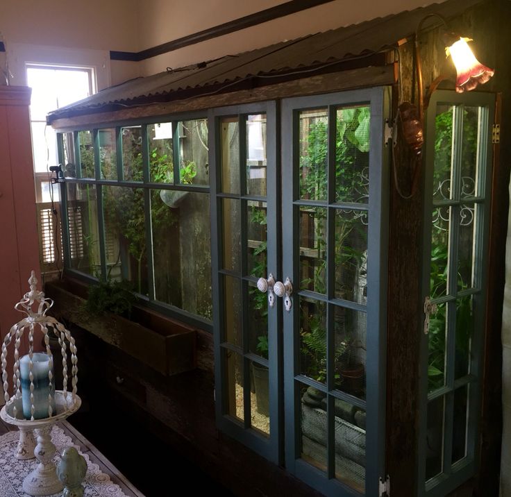 the inside of a house with many windows and plants in pots on top of it