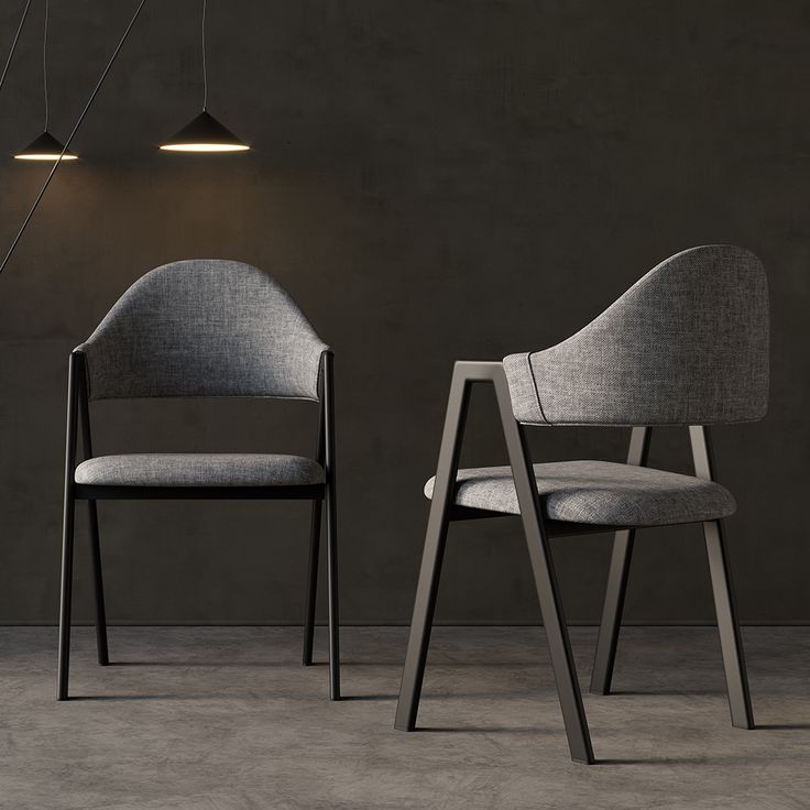 two gray chairs sitting next to each other in front of a black wall and floor