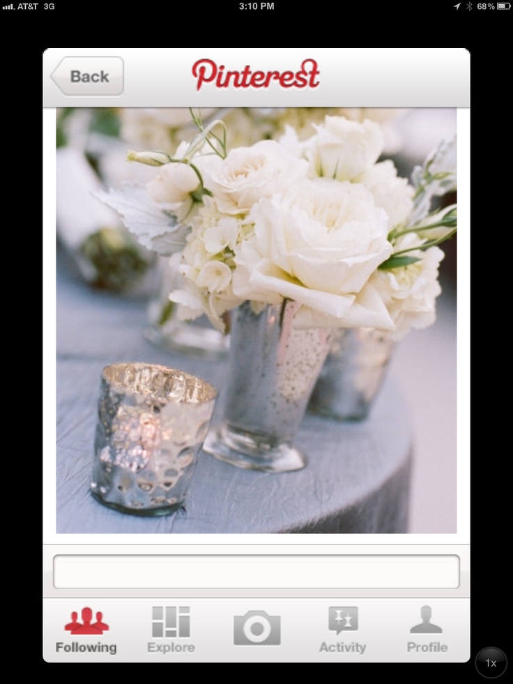 white flowers in silver vases sitting on a table with candles and votive cups